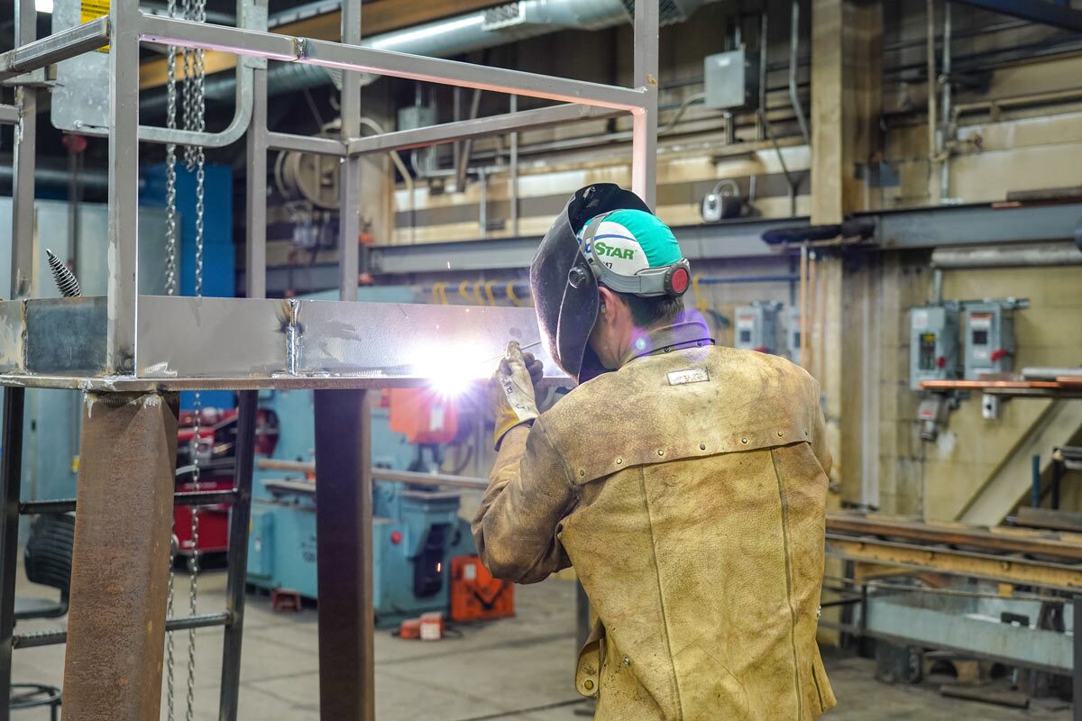Person welding with protective helmet and clothing